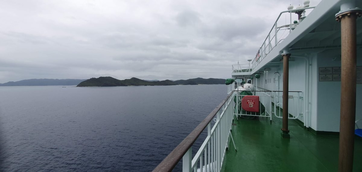 Side deck of the ferry with forested islands across the water on the way to Zamami