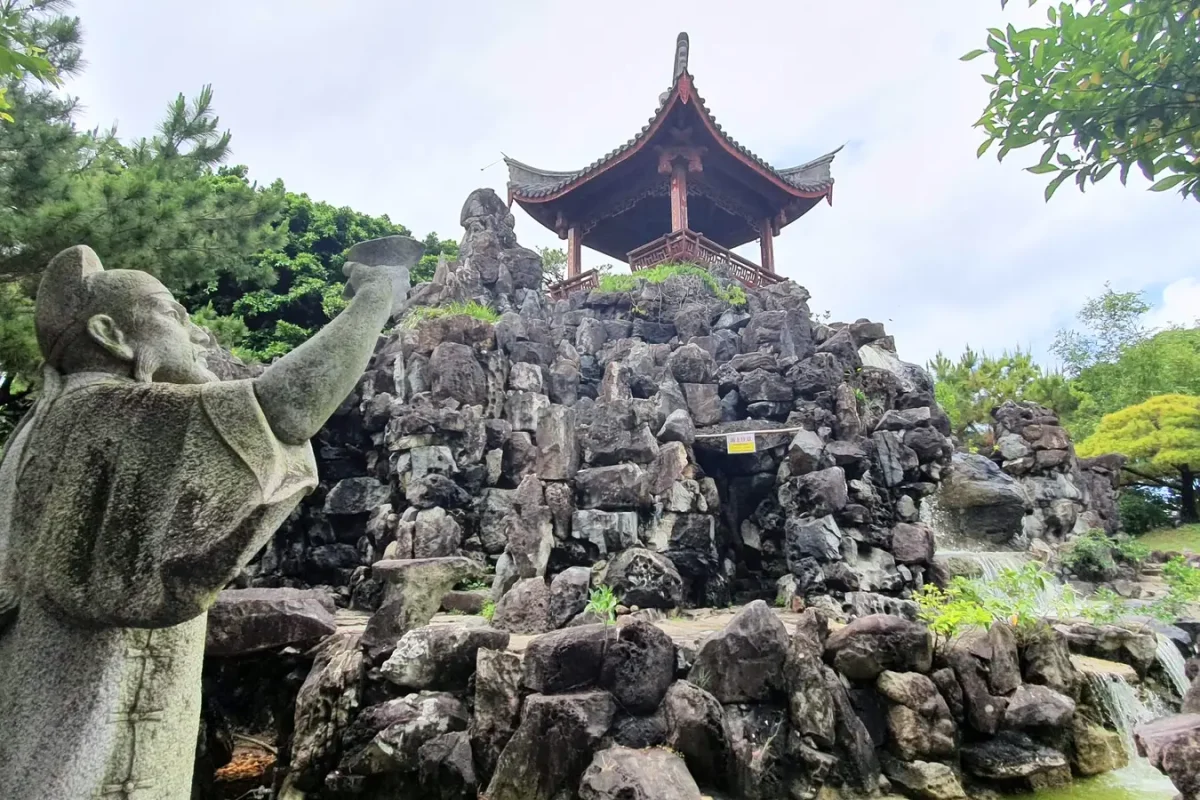 okinawa fukushu en garden waterfall and pavilion 11460 Stone statue, waterfall and rocky mound topped by a pavilion at Fukushu-en Garden