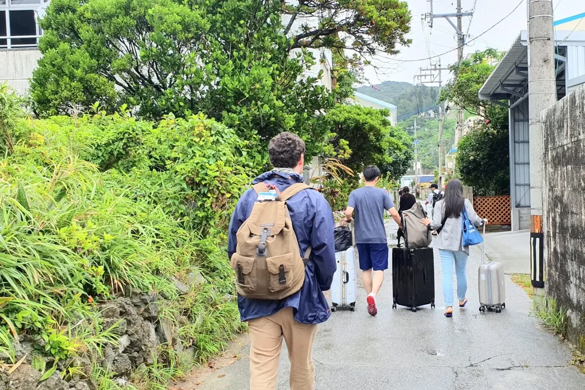 Gary carrying a backpack through a lane in Zamami village