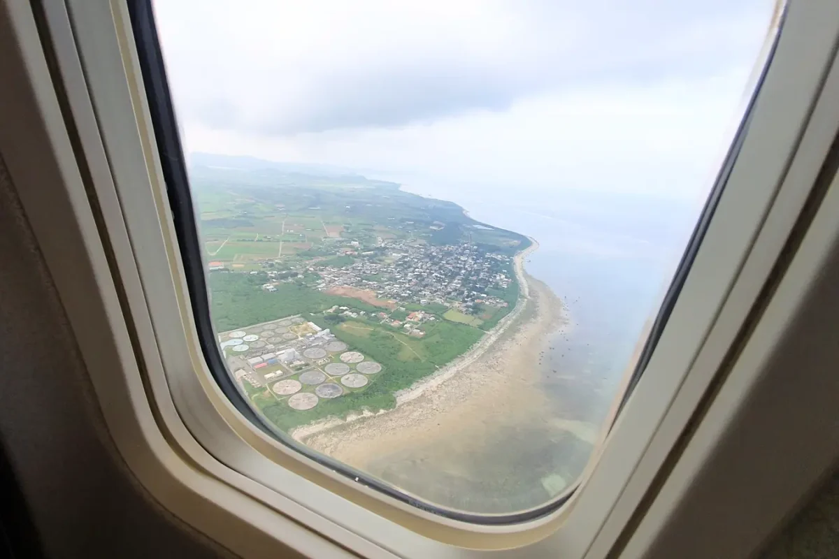 Coastline and fields seen through the aircraft window before landing on Ishigaki