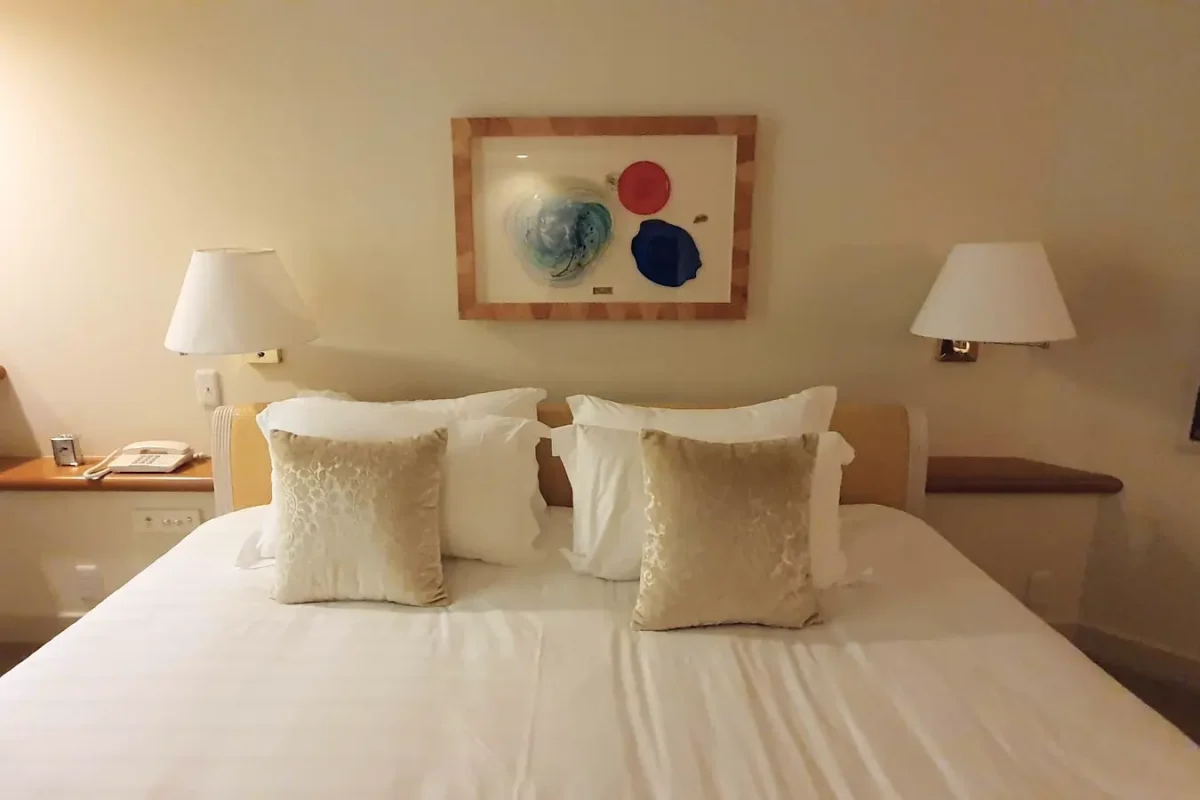 Bed with cushions and bedside lamps at The Naha Terrace