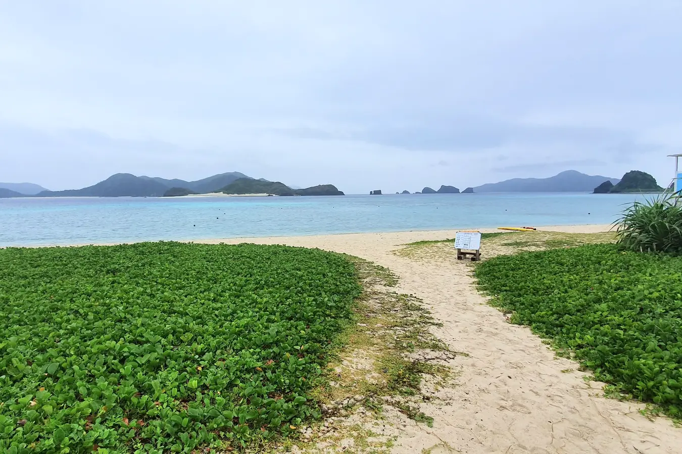 Sandy path through greenery onto Ama Beach with islands beyond