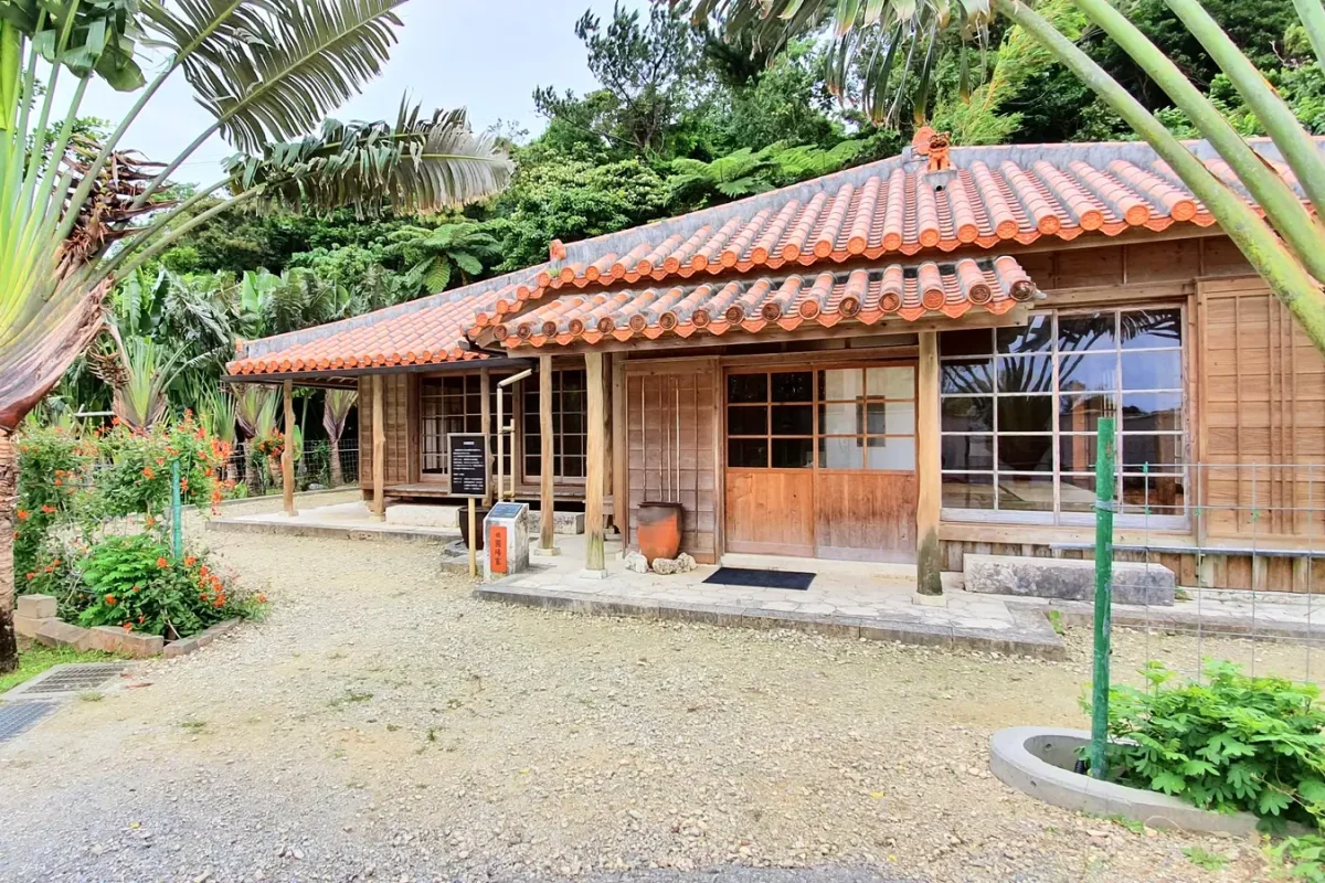 Traditional Okinawan house with a red tiled roof and wooden veranda at Ryukyu Mura